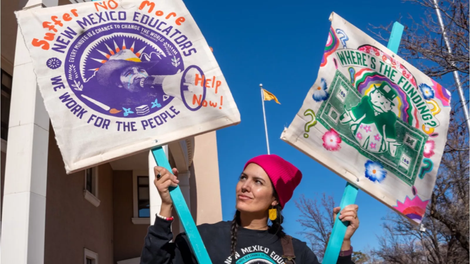 Educator holding signs demanding funding and help